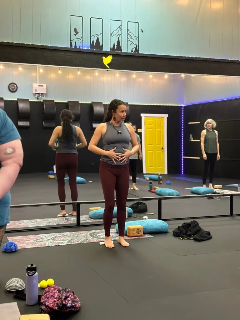Instructor guiding a breathwork class with hands on her belly
