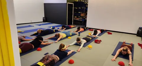 Students lying face down in a stretch with small balance domes