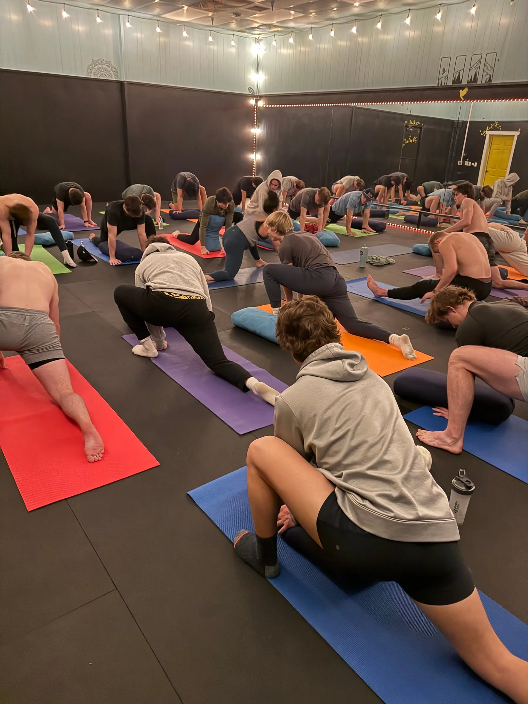 A full class holding low lunges on colorful mats