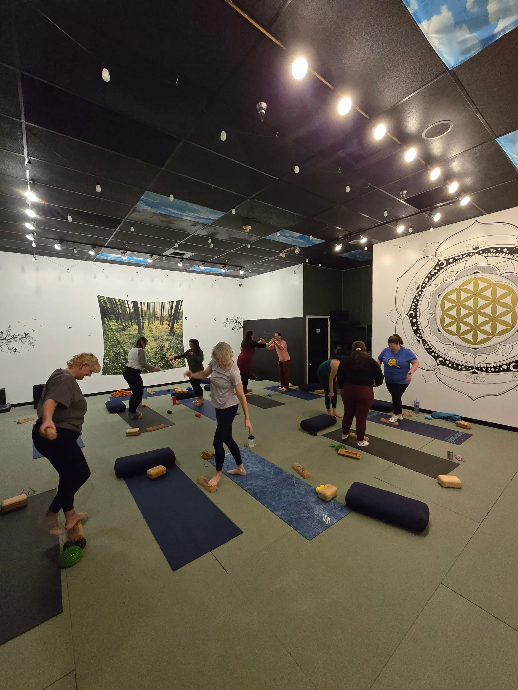A class stretching beside the studio’s mandala wall