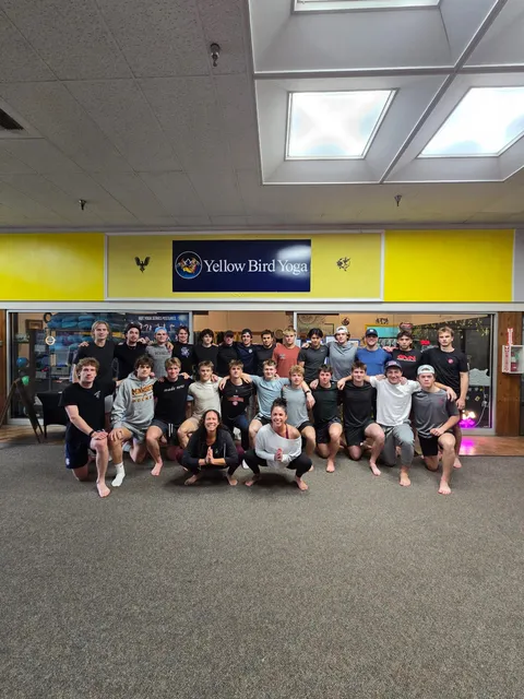 A large group gathered for a photo under the Yellow Bird Yoga sign