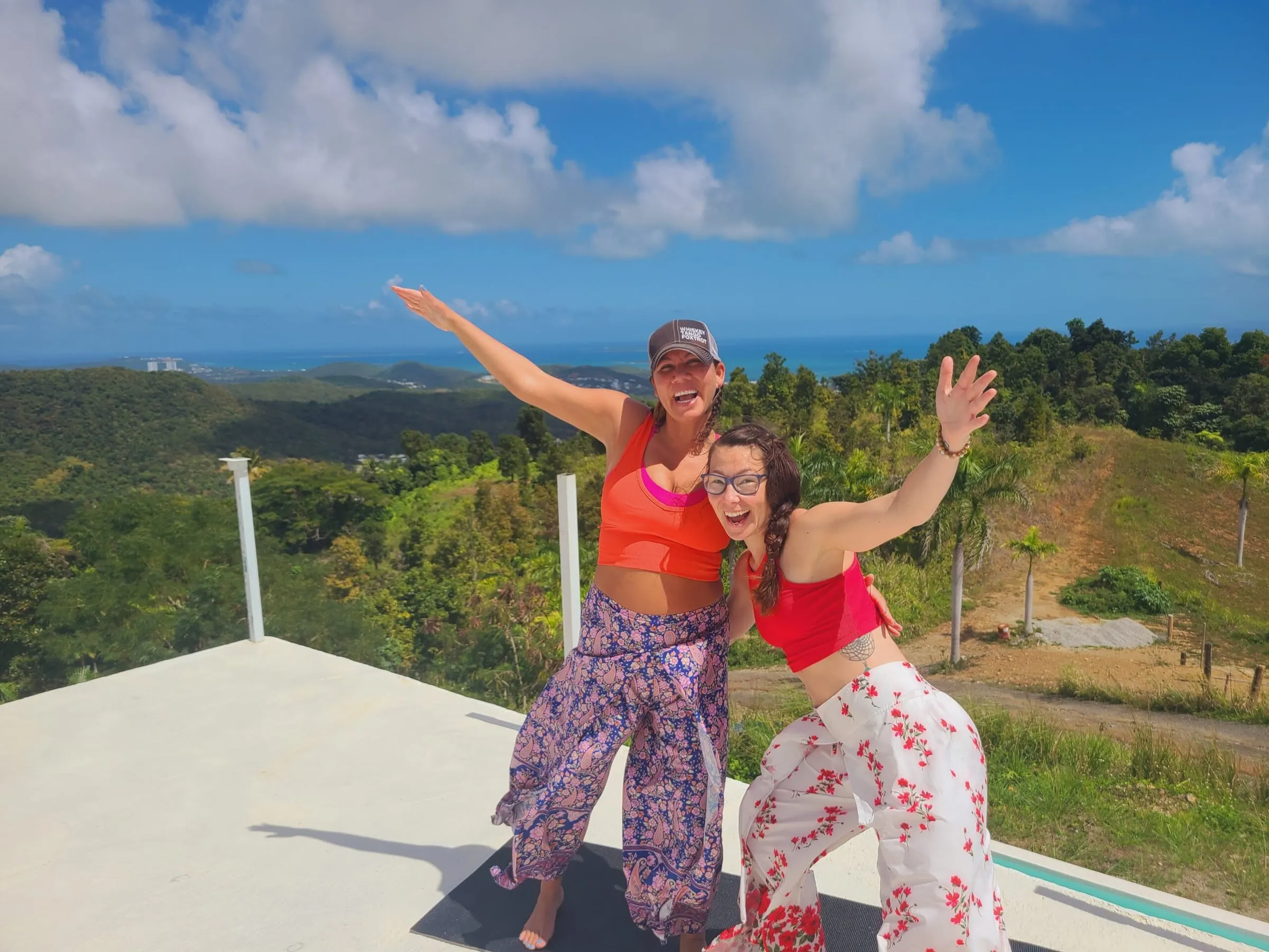 Two friends cheering on a sunny hilltop above the sea