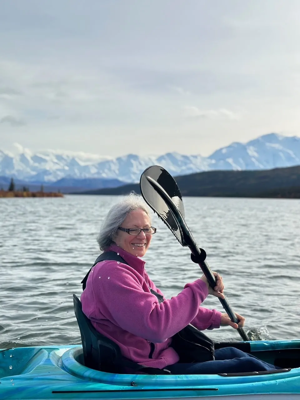 Smiling kayaker on a lake with snowy mountains behind